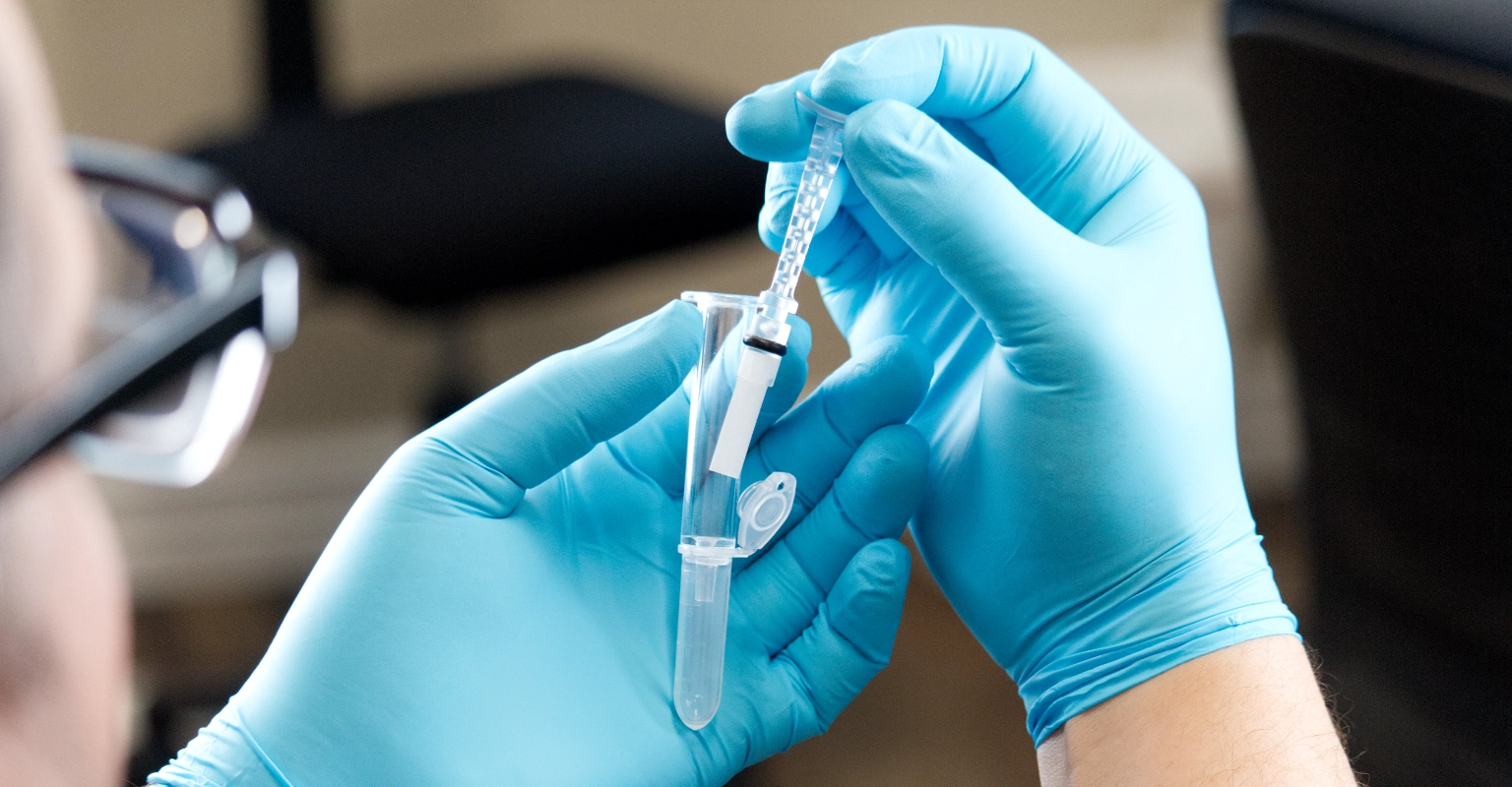 Gloved hands handling EZ Saliva QuickSwab for compliant lab confirmation